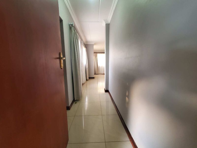 A clean, well-lit hallway featuring neutral wall tones, tiled flooring, and classic cornicing, providing a seamless transition between living spaces.