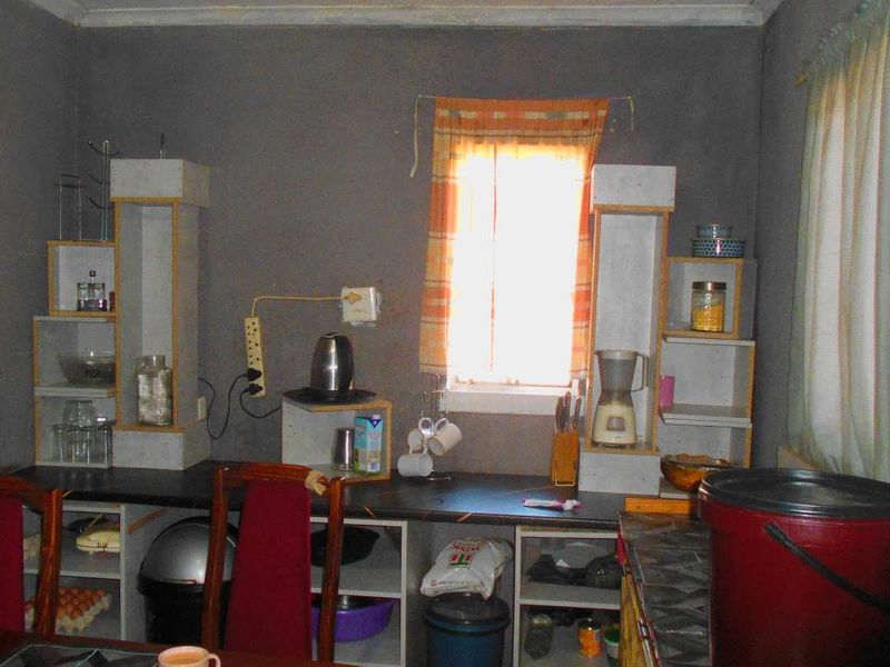 A small kitchen area featuring built-in shelving units and a countertop, requiring cosmetic updates and finish improvements.