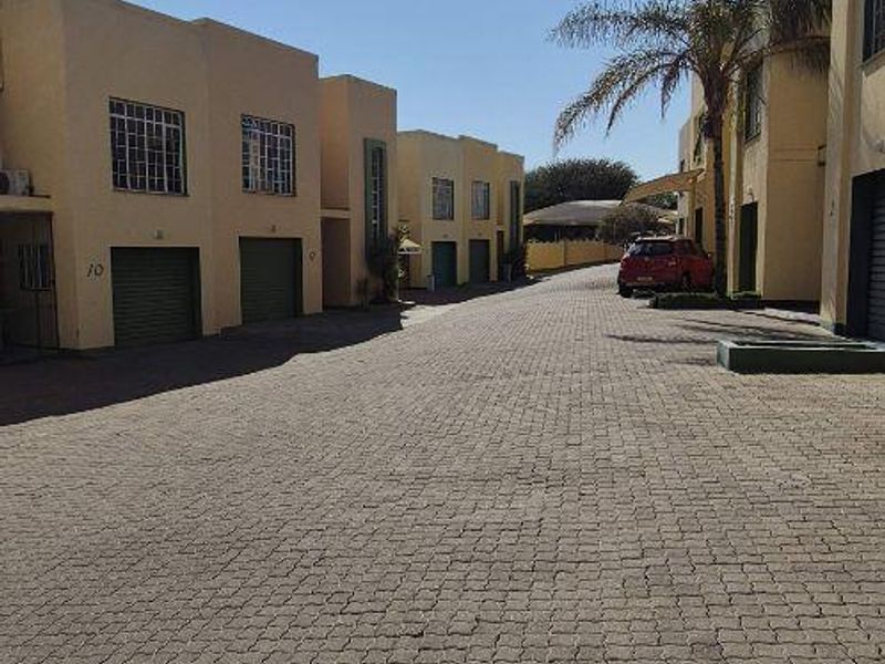 A view of the townhouse complex driveway featuring paved surfaces and multiple garage access points.