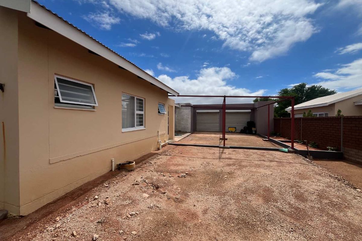 Rear exterior view showing a double garage with an unfinished ground area and exposed metal structural framing.
