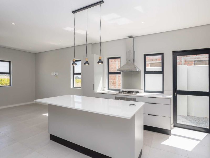 Modern kitchen featuring a central island, quartz countertops, gas hob, stainless steel extractor fan, and sleek cabinetry with neutral tiled flooring.