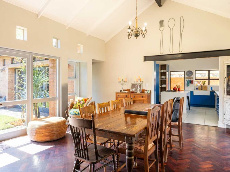 Spacious open-plan dining area featuring vaulted ceilings, herringbone timber flooring, and direct access to the garden, flowing into a functional kitchen space.