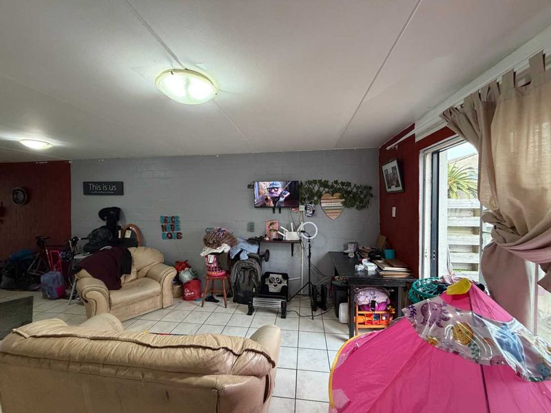 Living room area featuring ceramic floor tiles and a sliding glass door providing access to the exterior.