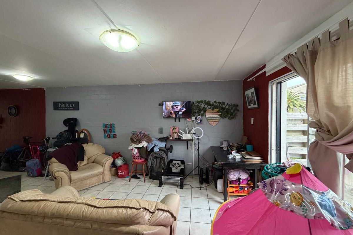 Living room area featuring ceramic floor tiles and a sliding glass door providing access to the exterior.