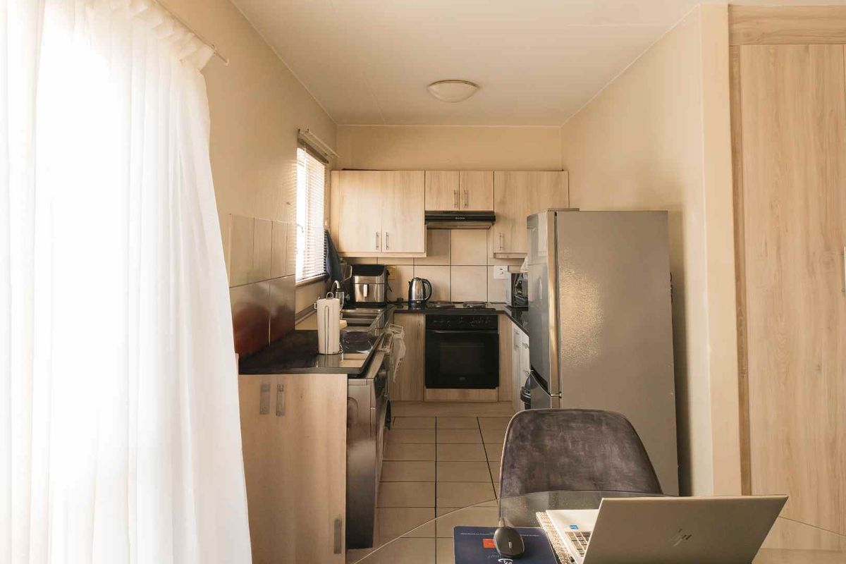 A compact kitchen featuring light wood-finish cabinetry, dark countertops, a built-in oven, and a tiled floor, offering a functional and efficient workspace.