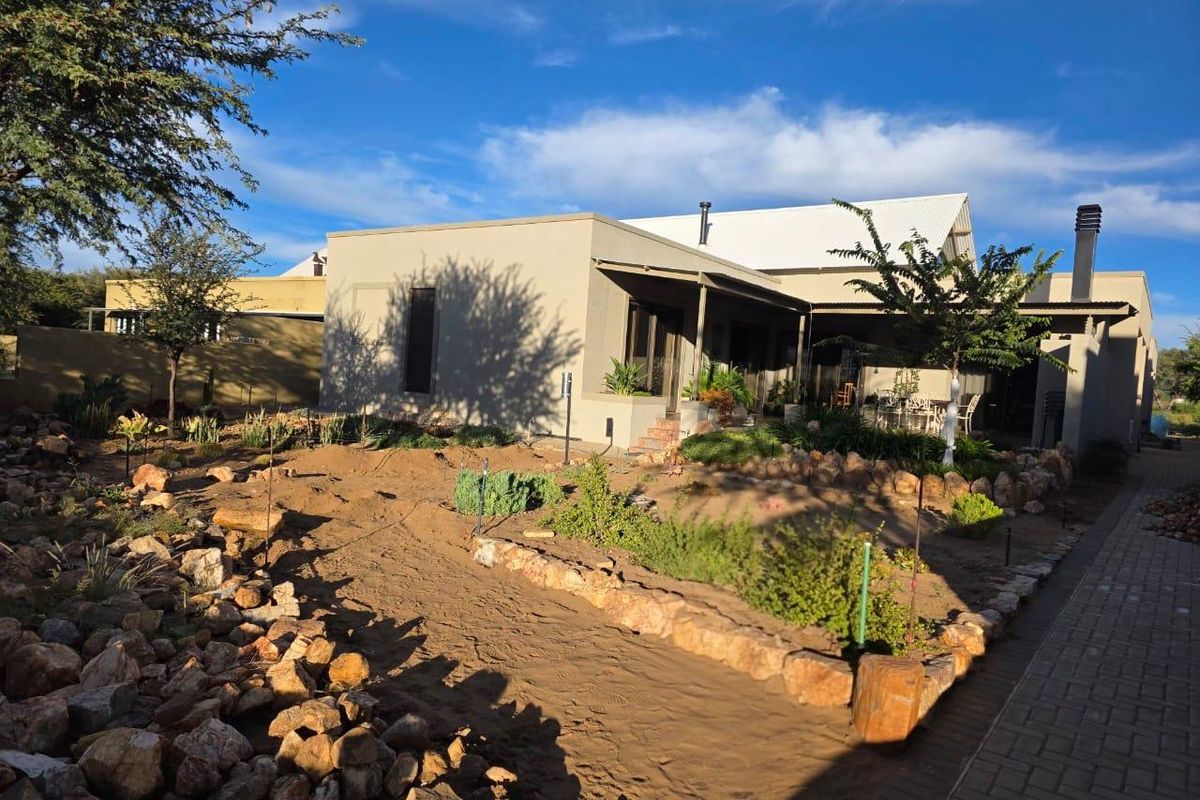 A view of the rear exterior of the house featuring a landscaped garden with stone borders and a covered patio area.