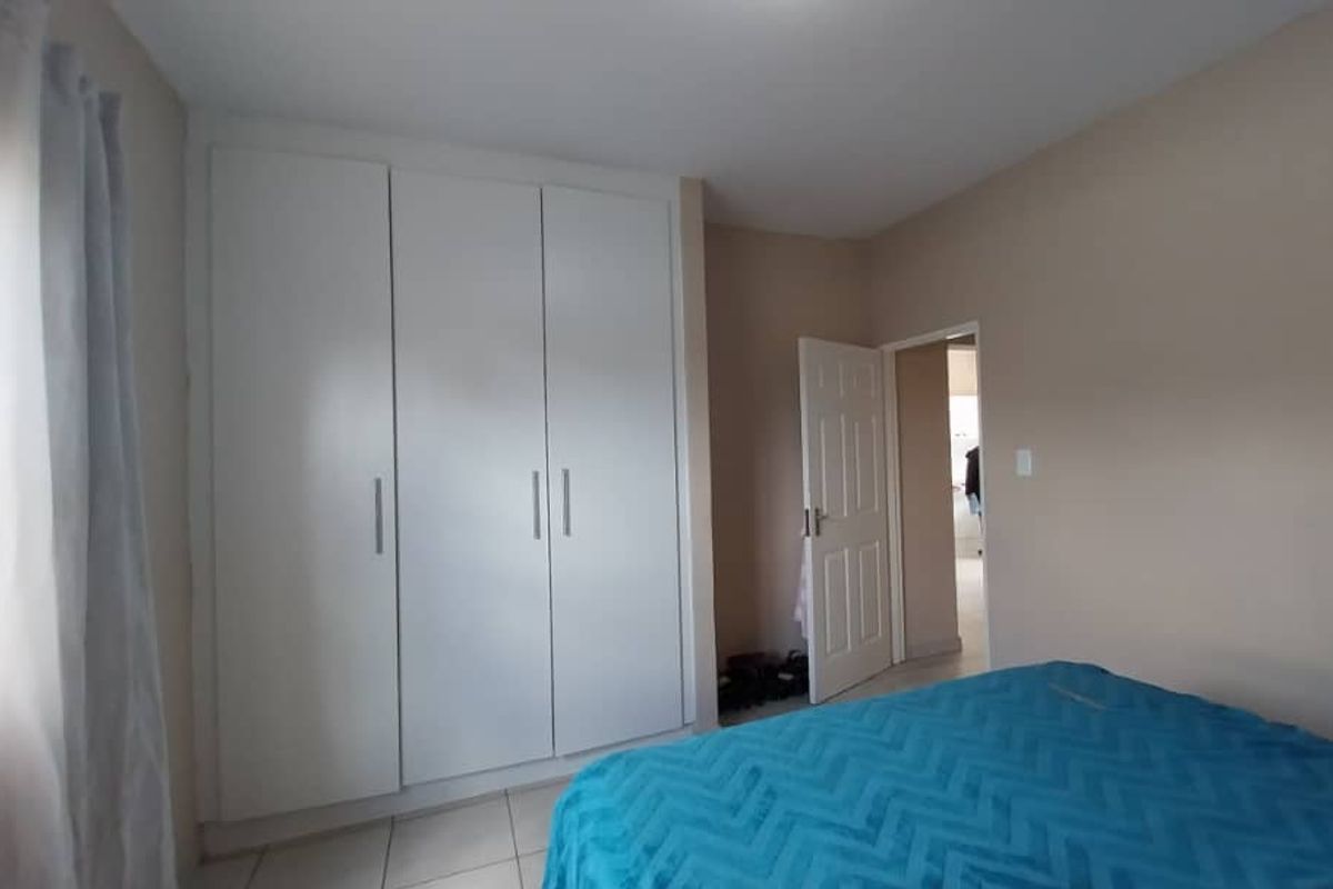 A bedroom featuring built-in white cabinetry and tiled flooring, offering a functional and neutral living space.