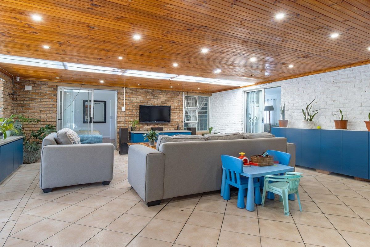 Spacious living room featuring a timber-clad ceiling with recessed lighting, a skylight, exposed brick walls, and tiled flooring with integrated cabinetry.