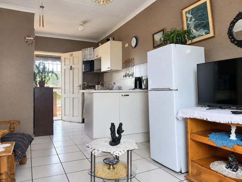 Open plan living area featuring a compact kitchen with tiled flooring and direct access to the exterior through a security gate.