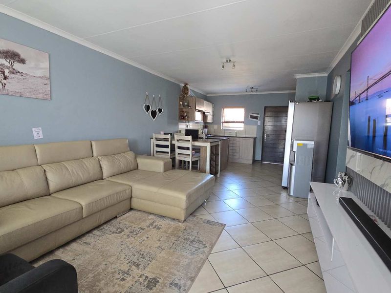 Open-plan living area featuring tiled flooring and a functional kitchen with cabinetry and a central island, creating a cohesive and versatile living space.