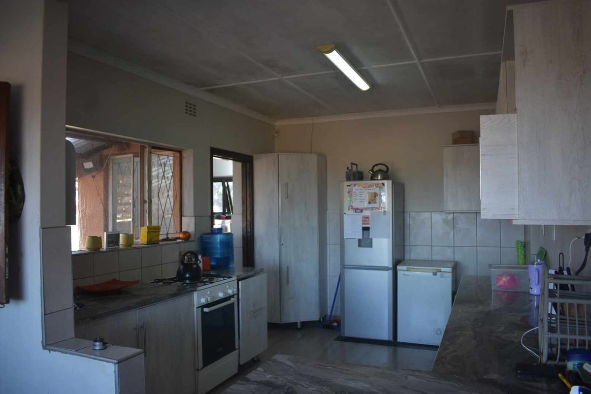 A functional kitchen featuring laminate countertops, built-in cabinetry, and a tiled backsplash, offering a practical layout with ample storage space.