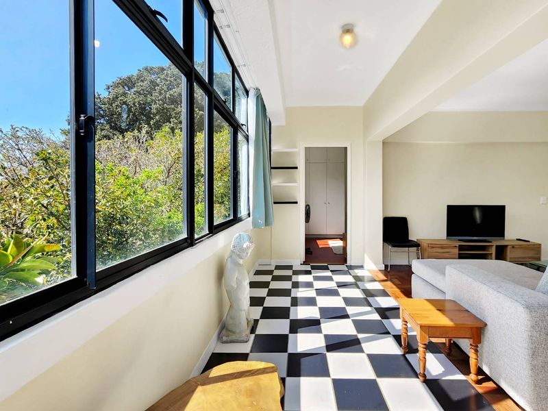 Bright living area featuring large black-framed windows, distinctive checkered flooring, and built-in storage, offering a unique and airy atmosphere.