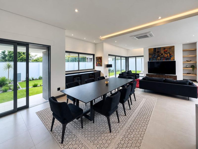 Spacious open-plan living and dining area featuring modern tiled floors, recessed lighting, ducted air conditioning, and large sliding glass doors opening to the garden.