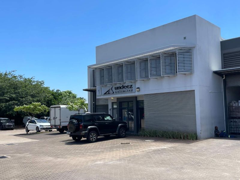Front elevation of a commercial mixed-use building featuring paved parking, metal louvre window shading, and a secure entrance.