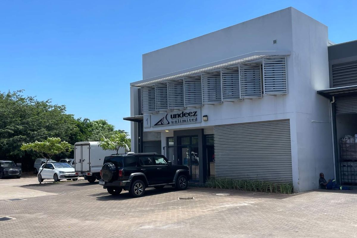 Front elevation of a commercial mixed-use building featuring paved parking, metal louvre window shading, and a secure entrance.