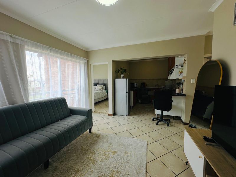 Open plan living area featuring tiled flooring and a connected kitchen space with built-in cabinetry and countertops.