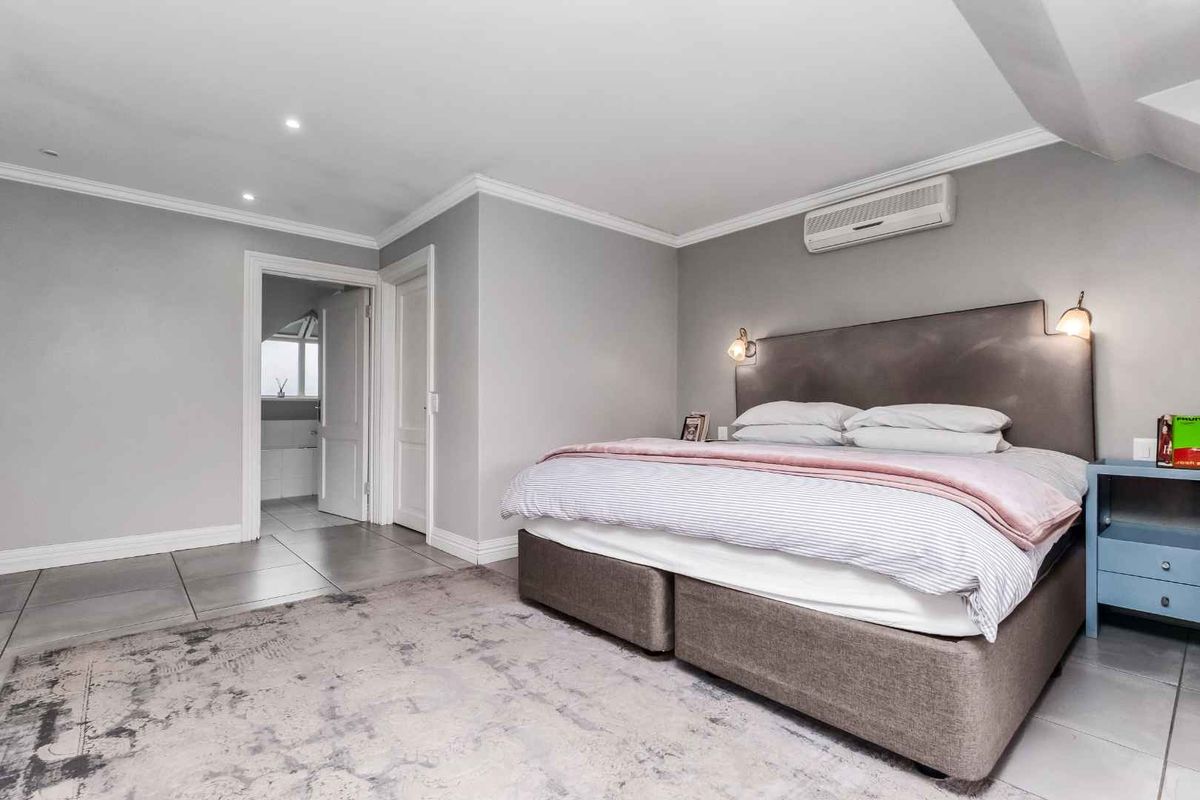 A well-maintained bedroom featuring tiled flooring, recessed downlighting, crown molding, and a wall-mounted split-system air conditioning unit.