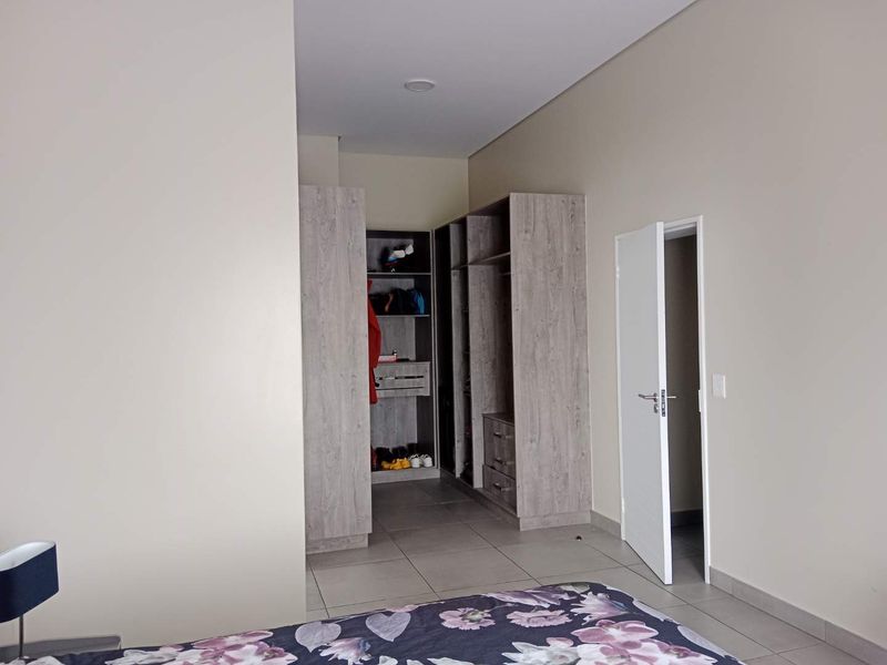 Bedroom featuring neutral walls, tiled flooring, and integrated built-in cupboards with open shelving and drawer storage.