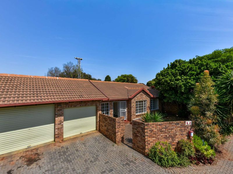 Front view of a townhouse featuring a double garage, brick facade, tiled roof, and a paved driveway with a private entrance.