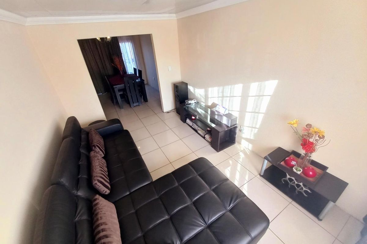 A view of the living room featuring tiled flooring and a transition into the adjacent dining area.