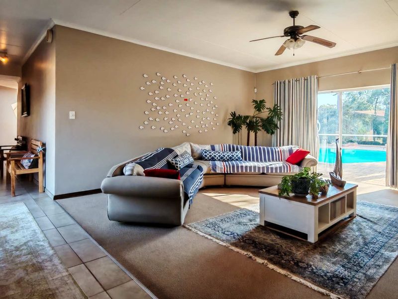 Spacious living room featuring a ceiling fan, neutral wall tones, and large sliding glass doors providing direct access to the outdoor pool area.