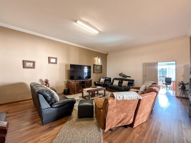 Spacious living room featuring laminate flooring and coving, providing a comfortable and functional area for relaxation and entertainment.
