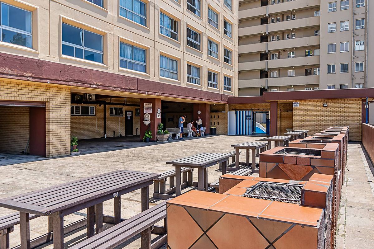 Outdoor communal entertainment area featuring built-in brick braai stations and paved terrace space within an apartment complex.