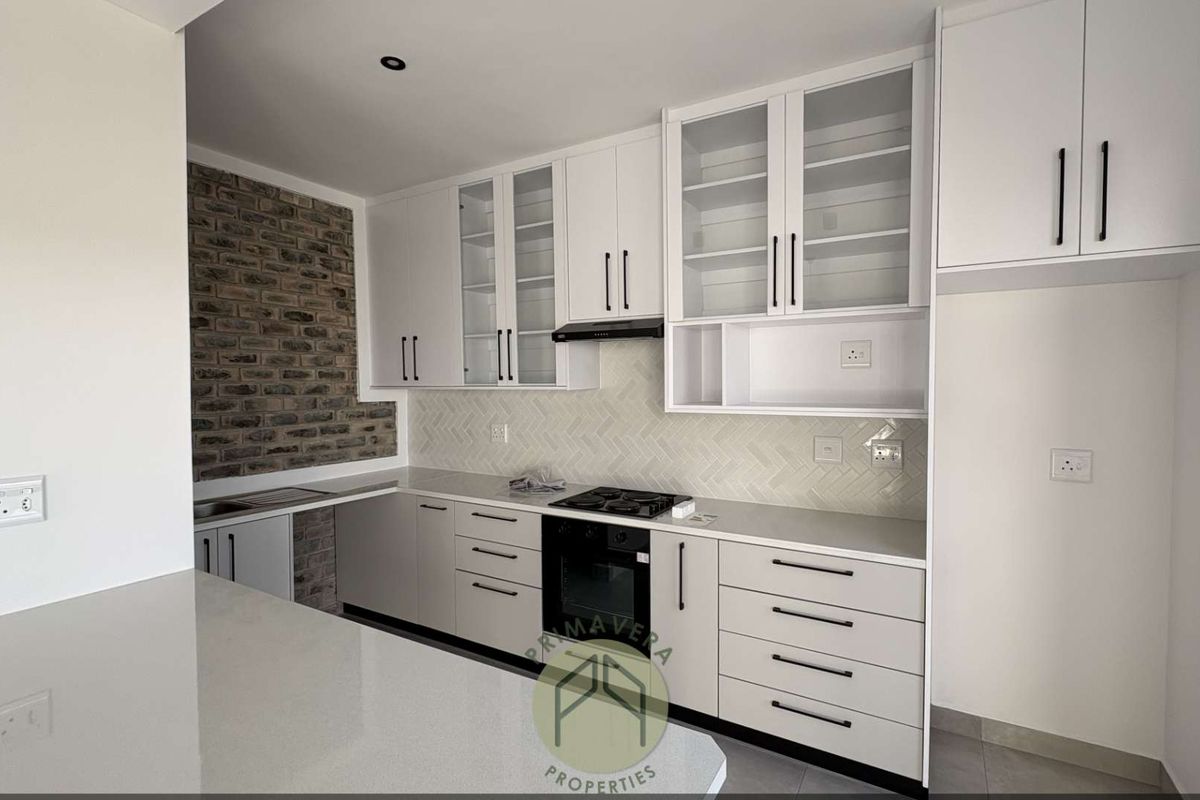 Modern kitchen featuring white cabinetry, stone countertops, a built-in oven, gas hob, extractor fan, and a stylish herringbone tile backsplash with exposed brick accent.