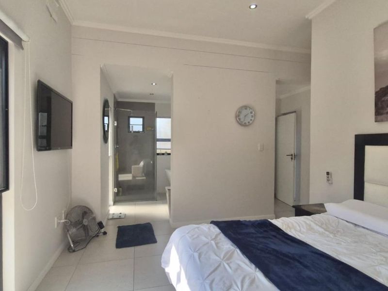 Spacious bedroom featuring tiled flooring, recessed lighting, and an integrated en-suite bathroom with a glass-enclosed shower.