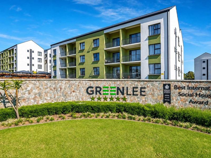 Front view of the Greenlee apartment complex featuring modern architecture, stone-clad signage wall, and well-maintained landscaped gardens.
