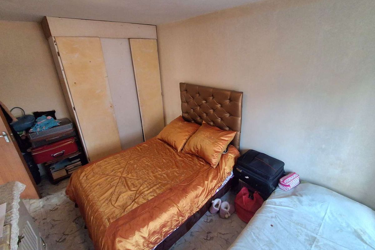 A bedroom featuring a built-in wardrobe and tiled flooring, requiring cosmetic updates to improve the overall aesthetic and condition.