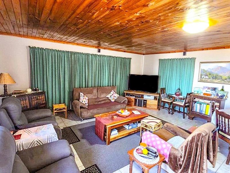 Spacious open-plan living and dining area featuring a warm timber tongue and groove ceiling and neutral tiled flooring.
