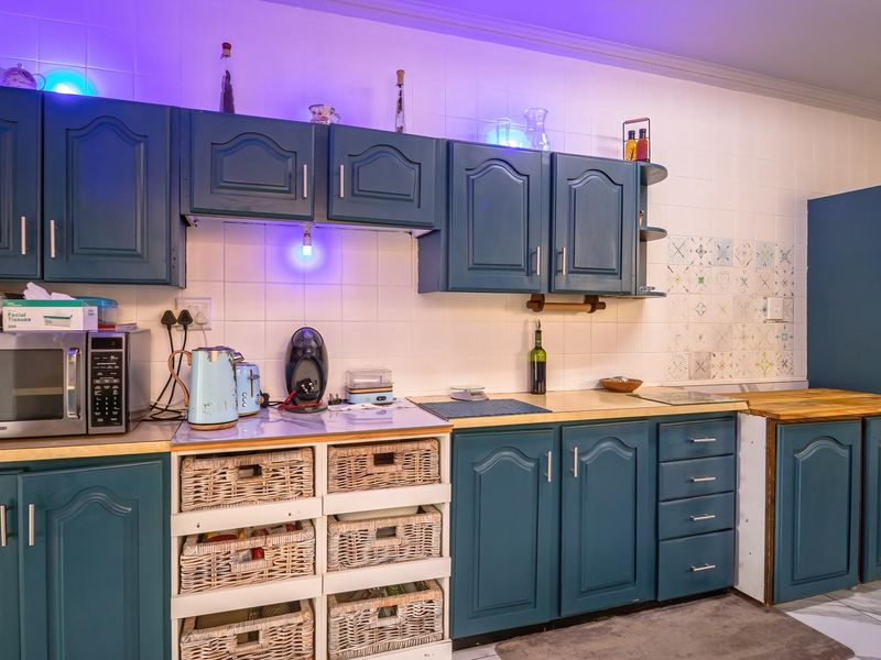 A functional kitchen featuring blue painted cabinetry, laminate countertops, a built-in double oven, and a tiled backsplash with decorative accents.