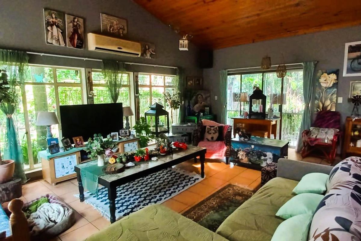 Spacious living room featuring a vaulted timber-clad ceiling, large windows providing natural light, and tiled flooring throughout.
