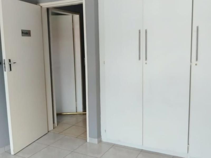 A clean, empty bedroom featuring neutral tiled flooring and white built-in cupboards, providing a versatile space ready for personalization.