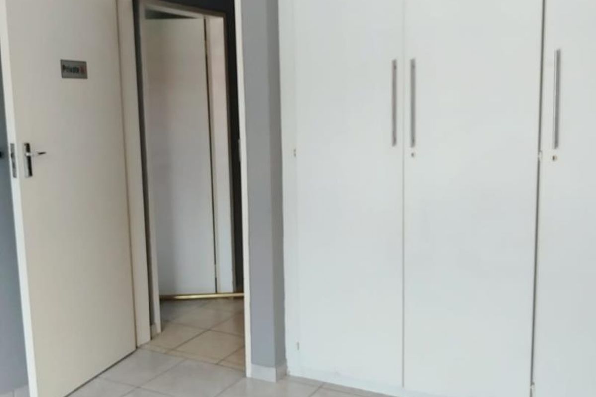 A clean, empty bedroom featuring neutral tiled flooring and white built-in cupboards, providing a versatile space ready for personalization.