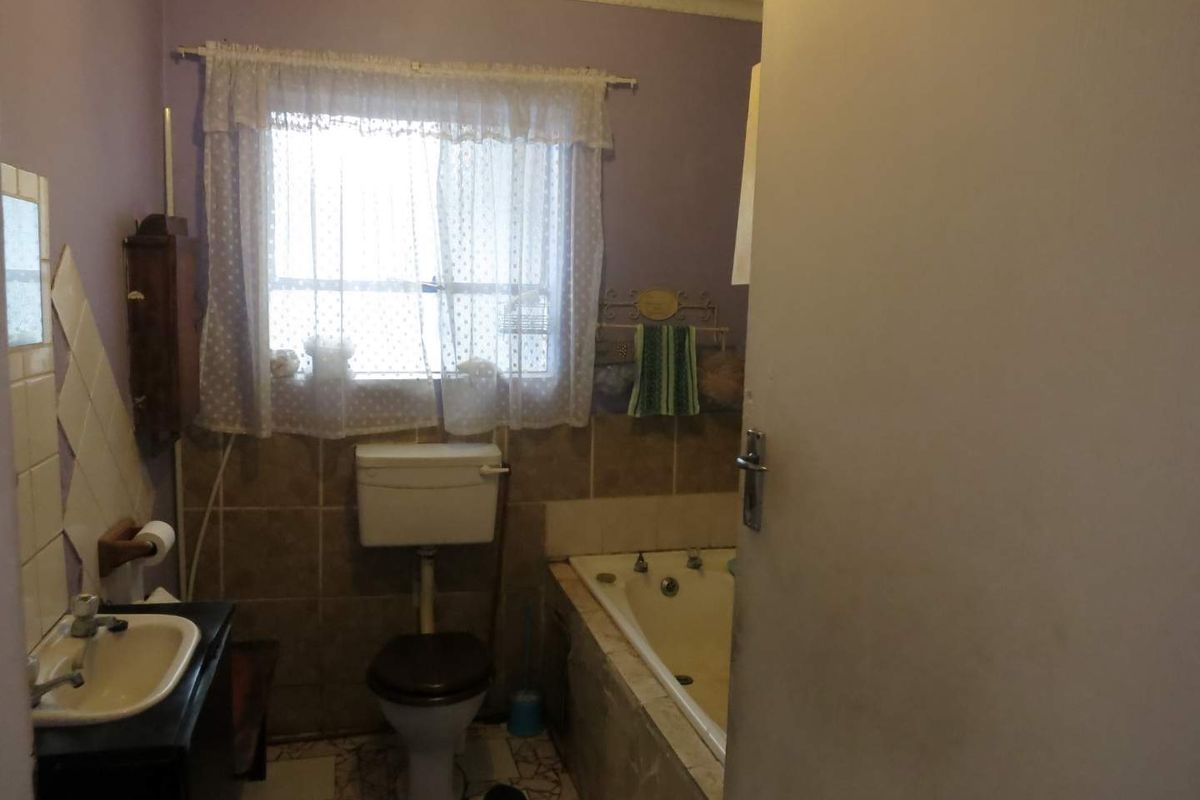 A dated bathroom featuring a built-in bathtub, toilet, and pedestal basin with tiled splashbacks, requiring modernization to improve its overall condition and appeal.