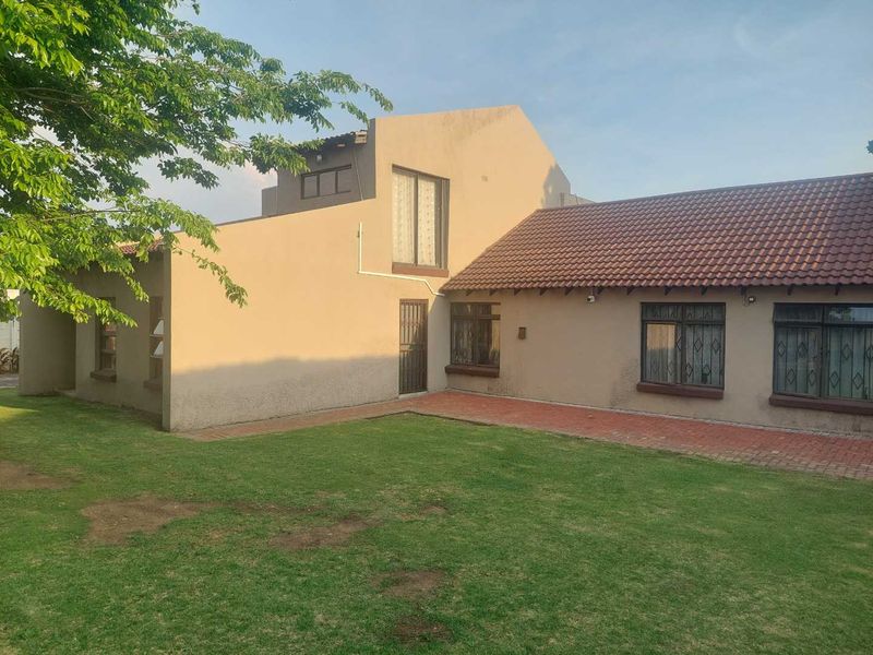 Rear view of the house featuring a tiled roof, brick paved patio area, and a private garden with established lawn.