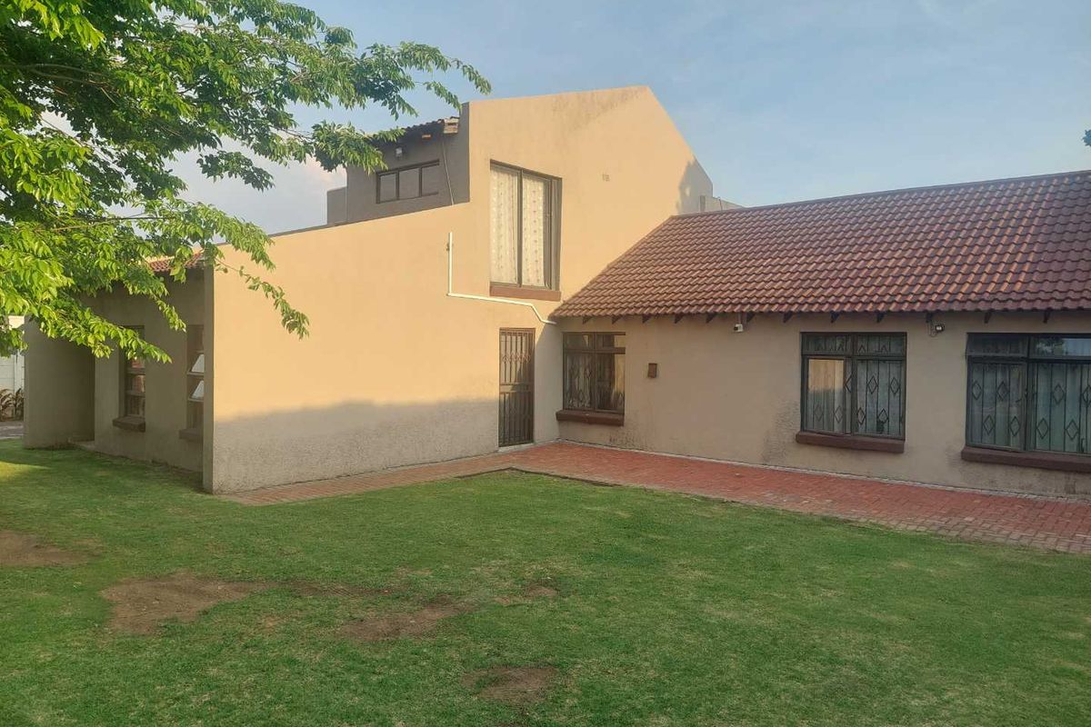 Rear view of the house featuring a tiled roof, brick paved patio area, and a private garden with established lawn.