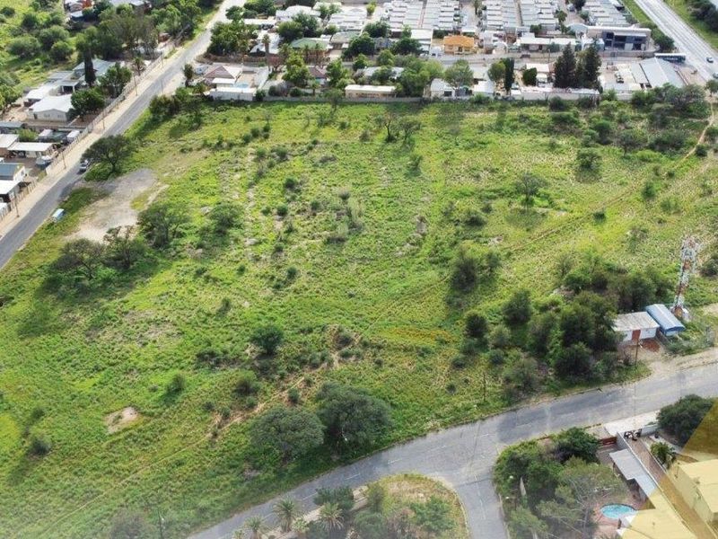 An aerial view of a large, undeveloped plot of land situated in a residential area, offering potential for future development.