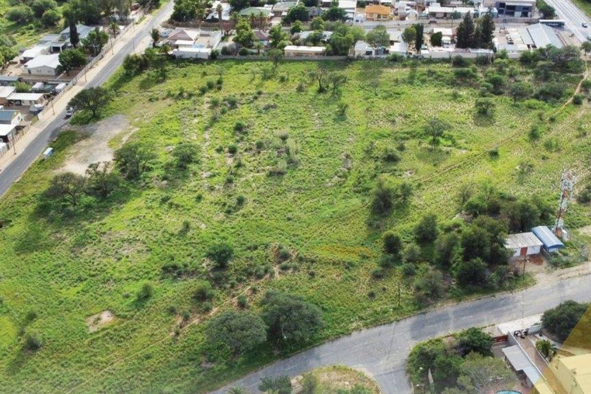 An aerial view of a large, undeveloped plot of land situated in a residential area, offering potential for future development.
