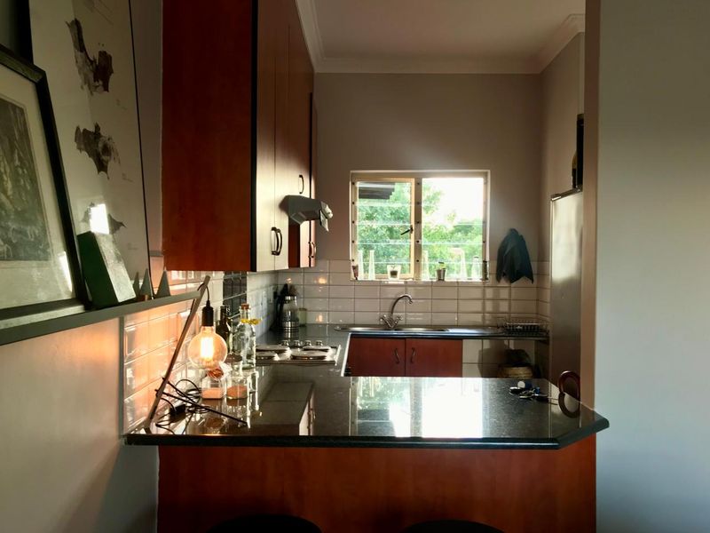 A functional kitchen featuring dark wood cabinetry, granite countertops, a subway tile backsplash, and a built-in hob with an extractor fan.