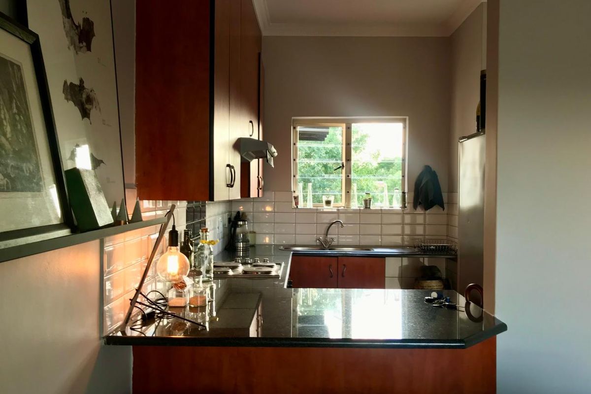 A functional kitchen featuring dark wood cabinetry, granite countertops, a subway tile backsplash, and a built-in hob with an extractor fan.