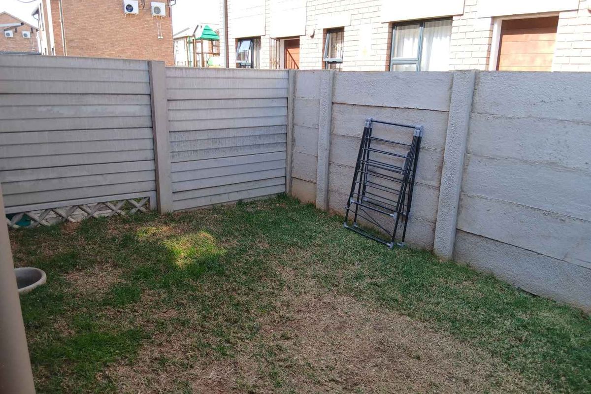 A small private rear garden area enclosed by precast concrete boundary walls, featuring a modest lawn space.