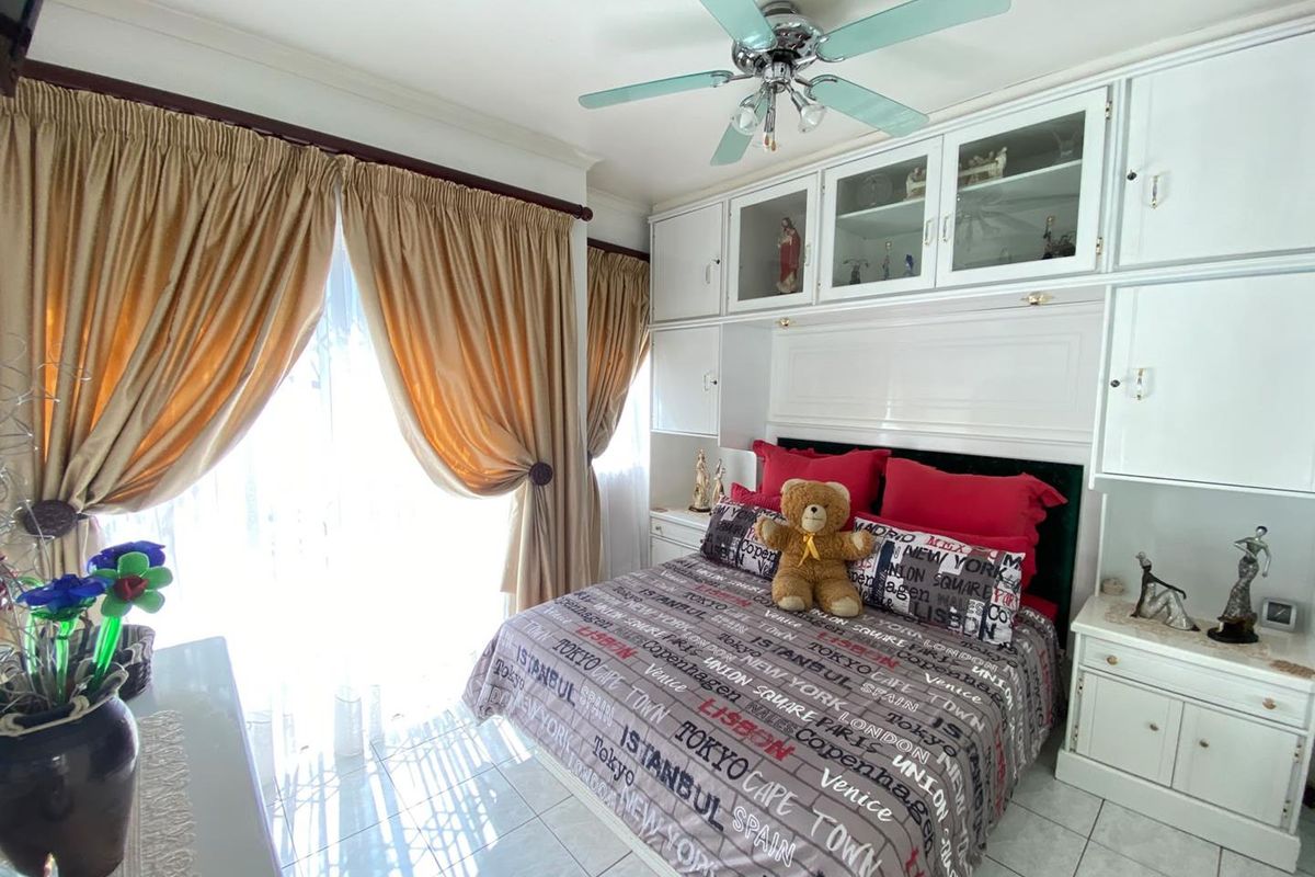 A bedroom featuring built-in cabinetry, tiled flooring, a ceiling fan, and a sliding door providing access to the exterior.