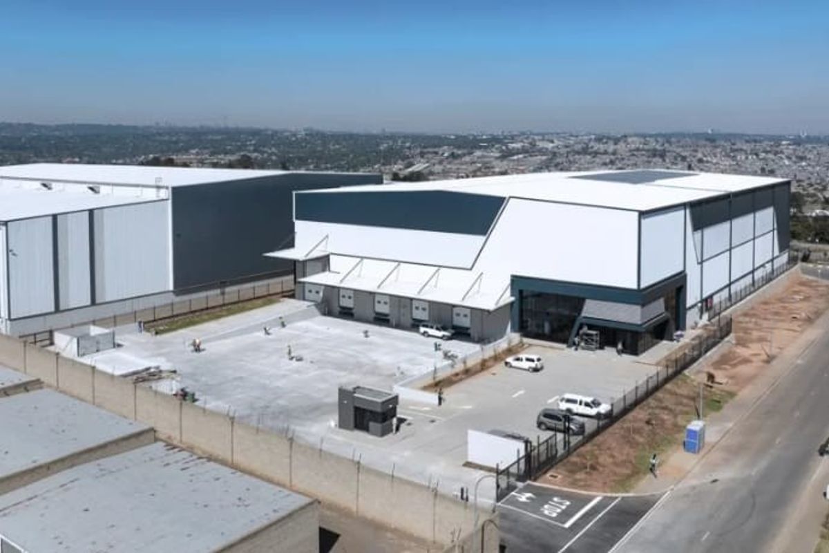 Aerial view of a modern industrial warehouse complex featuring large loading bays, paved yard space, and secure perimeter fencing.