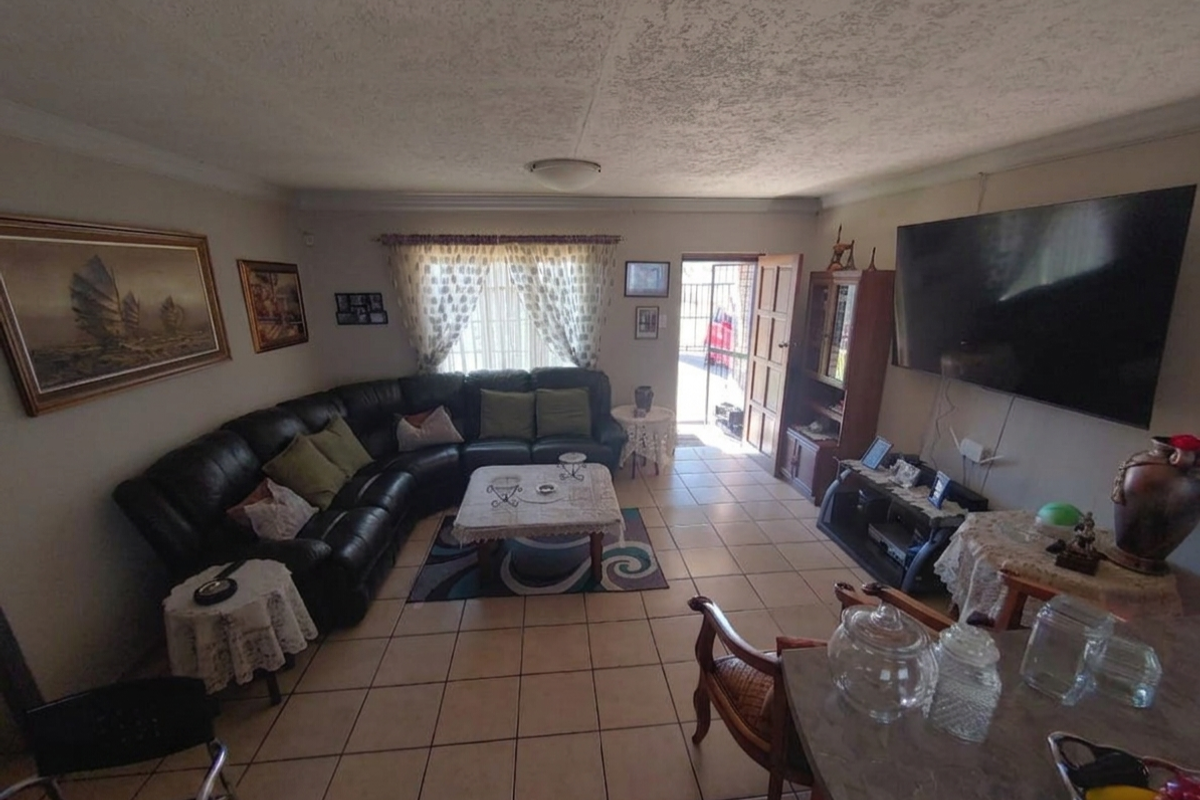 A living room featuring tiled flooring, coving, and direct access to the exterior through a security gate and timber door.