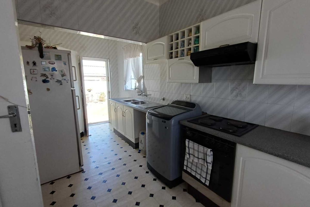 Functional kitchen featuring built-in cabinetry, integrated oven and hob, extractor fan, and direct access to the rear exterior.