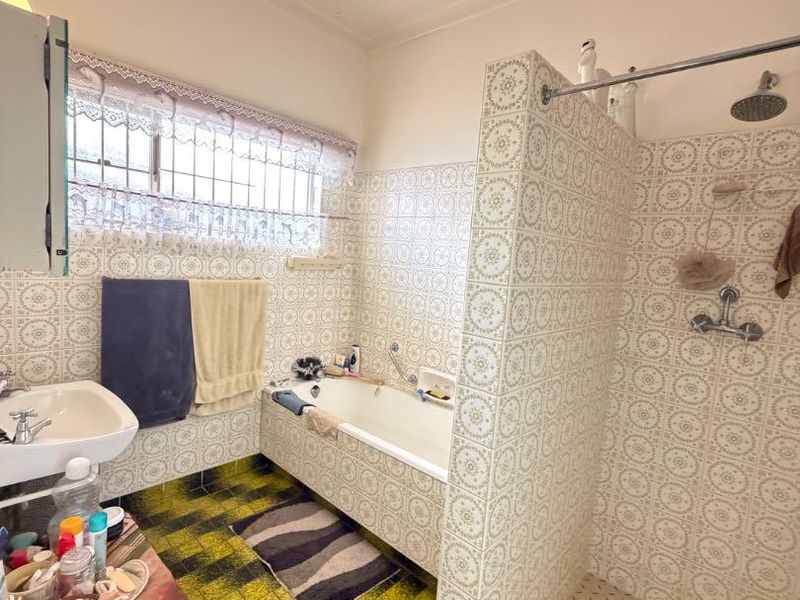 A dated bathroom featuring a built-in bathtub, a separate walk-in shower, and patterned wall tiles throughout.