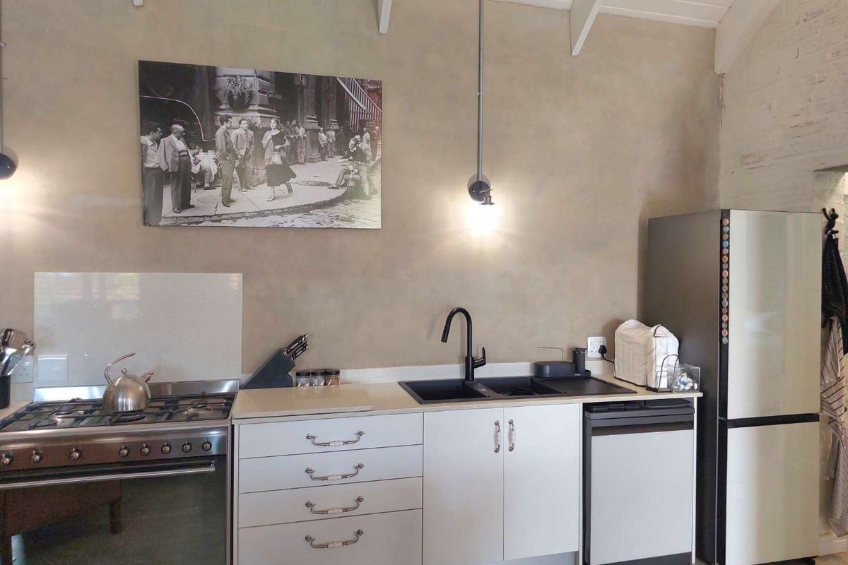 A functional kitchen featuring a gas stove, double sink, and modern cabinetry under exposed ceiling beams, offering a clean and practical workspace.